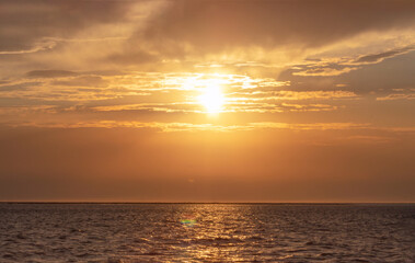 Colorful red sunset and bright sun on the horizon of the ocean beach.