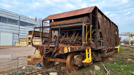 Abandoned old rusty freight industrial wagon on a factory railroad at sunny day. No people.