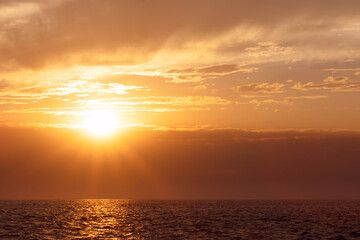 Colorful red sunset and bright sun on the horizon of the ocean beach.