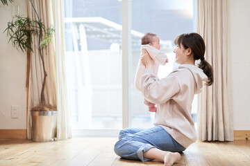 Obraz na płótnie Canvas リビングで赤ちゃんを抱えるアジア人のお母さん