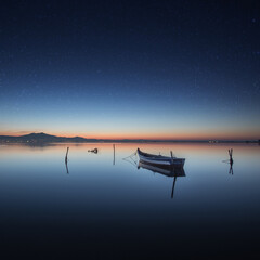 Boat on the sea with long exposure under a beautiful starry sky in the evening