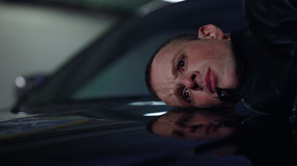 Police officer putting criminal face on car trunk. Sad man arrested by cop