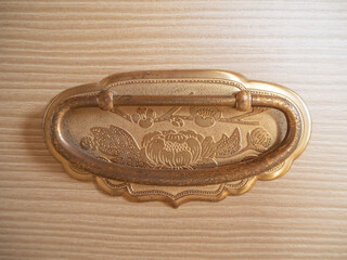 A golden handle on the antique drawer