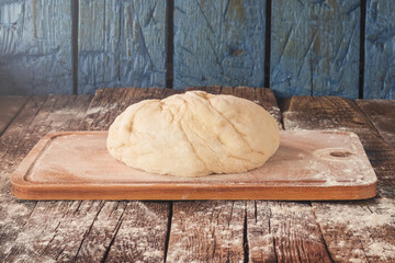 Empty space for text. Dough on the kitchen board. Rustic table. Tinted image.