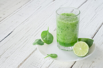 Empty space for text. Healthy lifestyle. Celery, spinach and lime smoothie. Drink glass, lime, spinach leaves.
