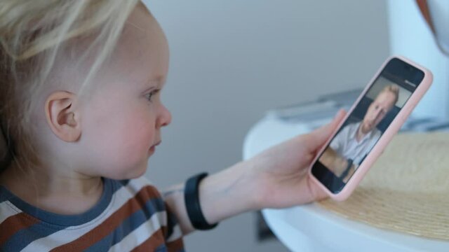 kid looks at dad on the smartphone screen