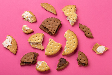 Pieces of chocolate chip cookies and biscuits with filling on a pink background close-up. Top view.