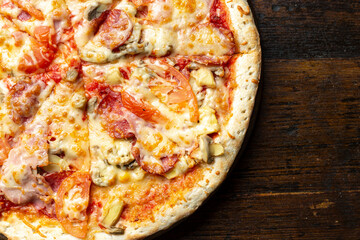 Fresh italian pizza with bacon, tomatoes, mushrooms and cheese on a wooden background.  Italian food. Space for text.