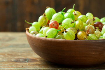 Sweet fresh gooseberry berry in a bowl on wood background.