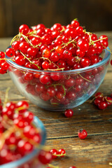 Sweet fresh red currant in a plate on wood table.