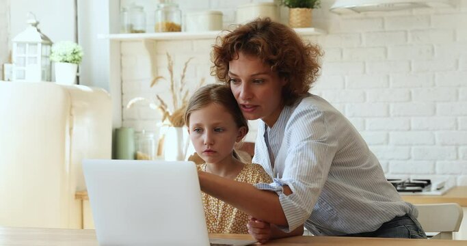 Mother helps to daughter with schoolwork using laptop, homeschooling due quarantine, internet education app usage, clap hands celebrate successful task accomplishment. Teach kid, study online concept