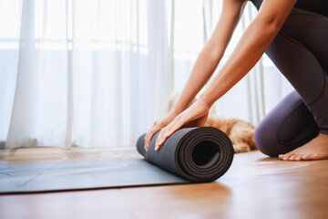 Close-up of woman hands unrolling roll black yoga mat for playing yoga at home