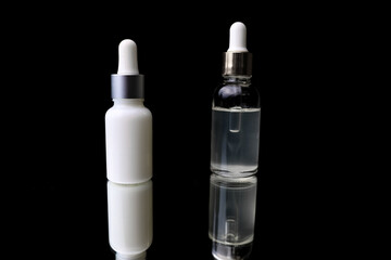 two cosmetic bottle with pipette on black background