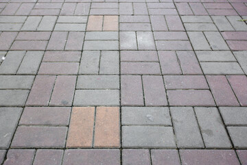 Perspective view of brick block stone pavement pattern surface in the city. People walking street footpath. Dirty pavement.