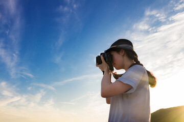 girl photographer takes a picture against the blue sky and sunset, the bottom view