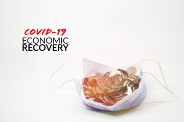 the economic concept of economic recovery covid-19 with a coin in a face mask