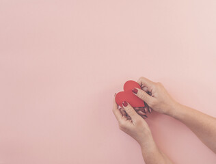Woman hands holding red heart on pink background, copy space. Flat lay, top view. Valentine or love, spring holidays, Christmas and birthday concept.