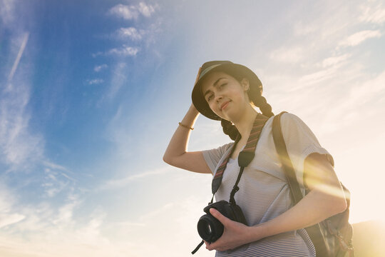 girl tourist with a backpack and a camera on the background of blue sky and sunset ,photos from the bottom up