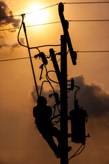 The silhouette of power lineman climbing on an electric pole with a transformer installed. And replacing the damaged hotline clamp, bail clamp, dropout and surge arrester that causes a power failure.
