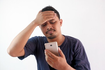 upset man holding phone with hand on forehead, stressed guy looking smartphone screen