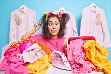 Funny millennial Asian woman makes grimace crosses eyes sticks out tongue wears dirty clothes after...