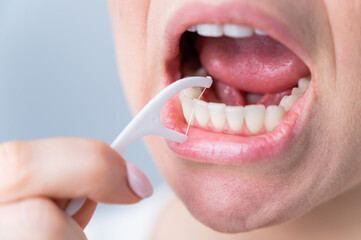 Fototapeta premium Caucasian woman brushing teeth with toothpick with dental floss on white background.