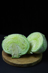 Cabbage on a dark background. Cabbage cut into two halves on a black background. Young fresh cabbage. Healthy diet