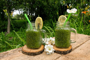 Homemade smoothies with fresh kiwi, spinach, lime and Basil in two glass jars on a wooden table in the garden. Healthy eating concept. Detoxification, cleansing, vegetarian and Keto diet. Super food. 