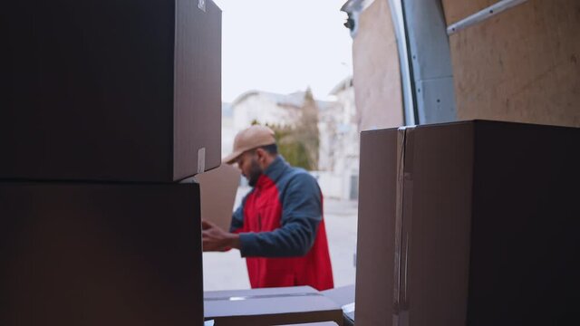 Young courier unloading parcels from the truck. High quality 4k footage