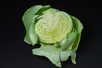 Fototapeta premium Cabbage on a dark background. Half of cabbage on a black background. Young fresh cabbage. Healthy diet