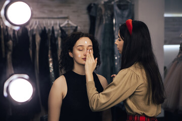 Make up talanted artist doing maquillage to woman. Visagist using brushes shadows facial professional cosmetics for makeup. Beauty industry studio, image with copy space.
