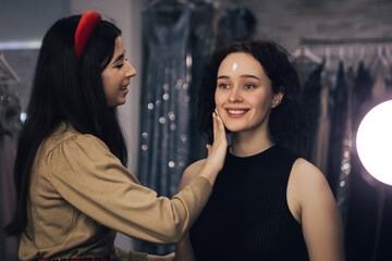 Make up talanted artist doing maquillage to woman applies cream. Visagist using brushes shadows facial professional cosmetics for makeup. Beauty industry studio, image with copy space.

