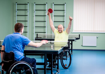 Fototapeta na wymiar Adult disabled men in a wheelchair playing table tennis