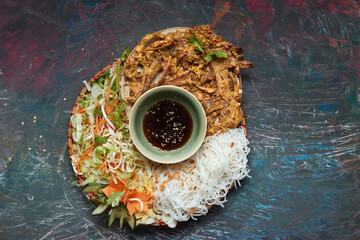 A large portion of traditional grilled duck with rice noodle, served with soy sauce and salads