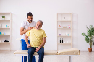 Old male patient visiting young male doctor chiropractor