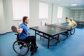 Adult disabled men in a wheelchair playing table tennis