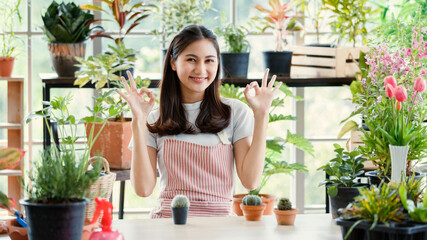 Girl long black hair wear t shirt pink stripe pattern apron ok action look very cute smiling standing in white mirror room. Living surround by air filtering plant pots colorful flower sunlight spring.