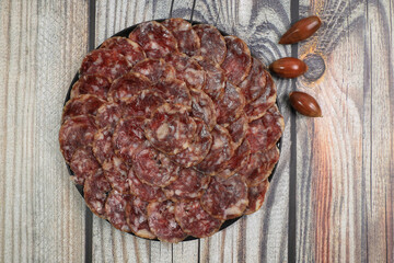 Ration of acorn-fed Iberian sausage 100% acorn in black plate decorated with acorns and wood background