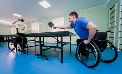 Adult disabled men in a wheelchair playing table tennis