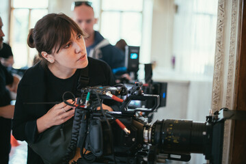 Female director of photography with a camera on a movie set. Professional videographer on the set...
