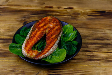 Grilled salmon steak with spinach on wooden table