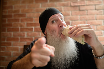 Man with long gray beard eating taco - 428555979