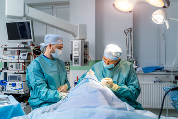 Team of surgeons operating person. Men in protective uniform in modern hospital room.