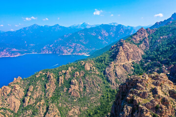 Aerial view of beautiful view of sunlit red mountains and the Mediterranean Sea with the Bay of Porto in Calanches area on Corsica island. Tourism and vacaions concept. Les calanches de Piana, Corsica