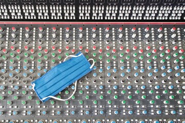 Blue mask laying at the eq section of an audio mixing desk (console), medical mask for protection...