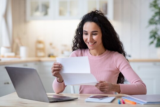 Portrait Of Excited Happy Woman Reading Letter In Kitchen