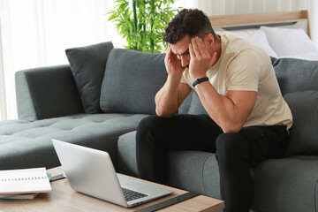 Fototapeta premium Thoughtful, serious Caucasian businessman working on laptop at home. Solving work problems and finding business inspiration concept.