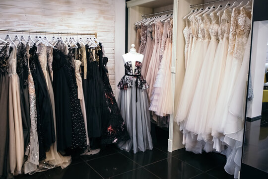 Beautiful collection wedding dresses various colors hanging on a hanger in a clothing store shop shopping mall. Fashion fancy stylish exhibition. Image with copy space.
