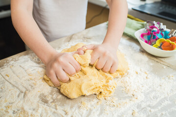 Child's hands kneading dough at home in the kitchen. Cooking at home