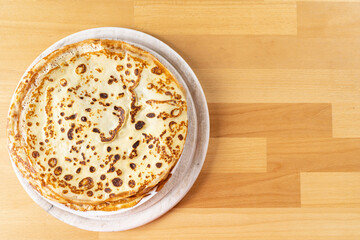 White plate of pancakes sitting on a beech wood table